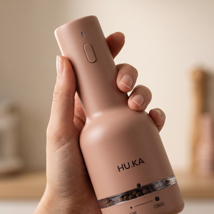Dłoń trzymająca młynek HU.KA Pulse Warm Clay — przycisk na korpusie i oznaczenia FINE i COARSE