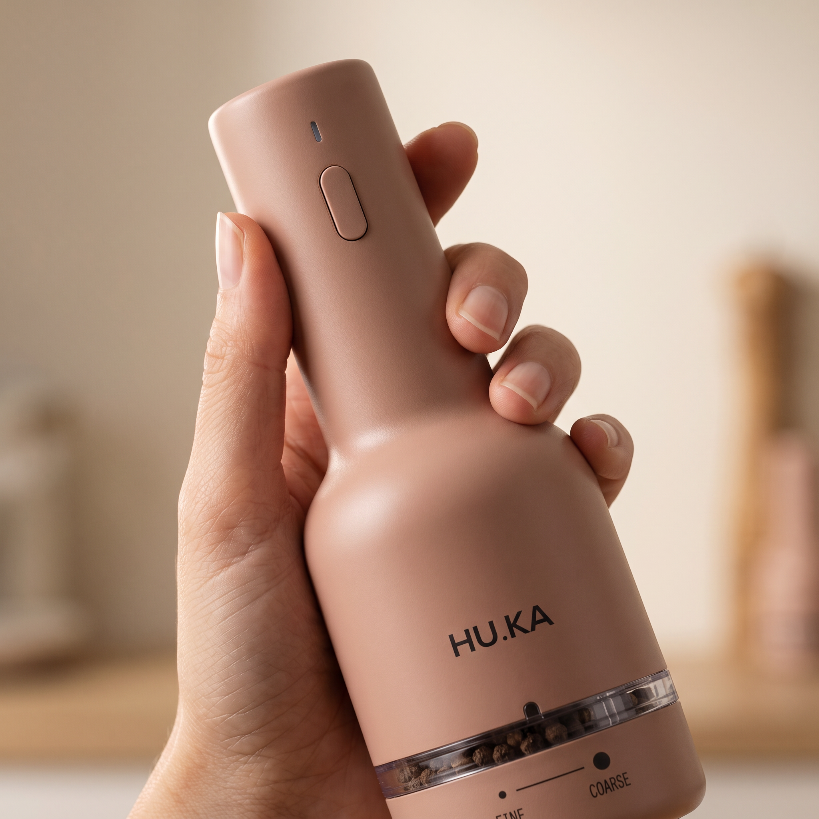Dłoń trzymająca młynek HU.KA Pulse Warm Clay — przycisk na korpusie i oznaczenia FINE i COARSE